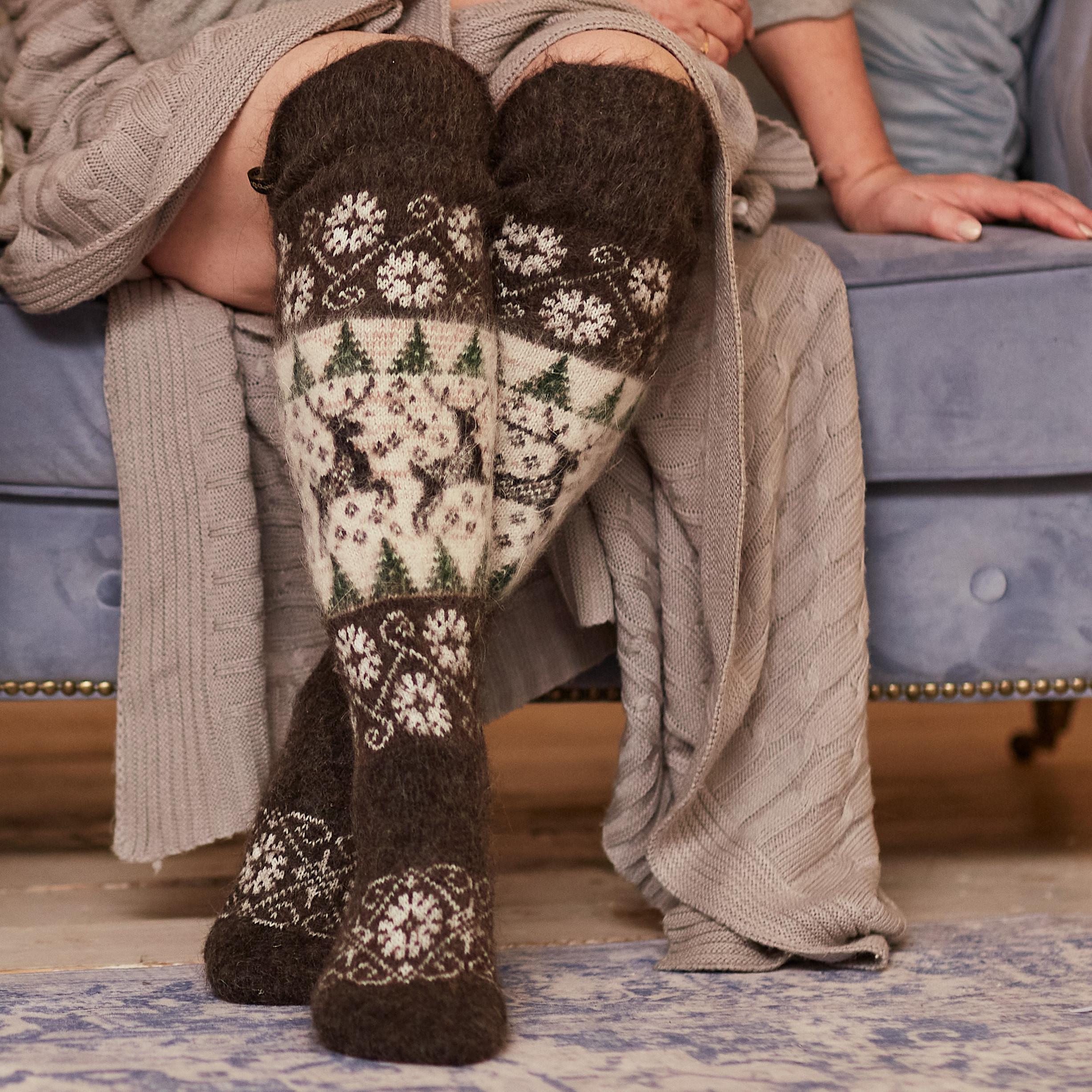 Woman sitting on a couch wearing black and white over-the-knee goat hair socks.