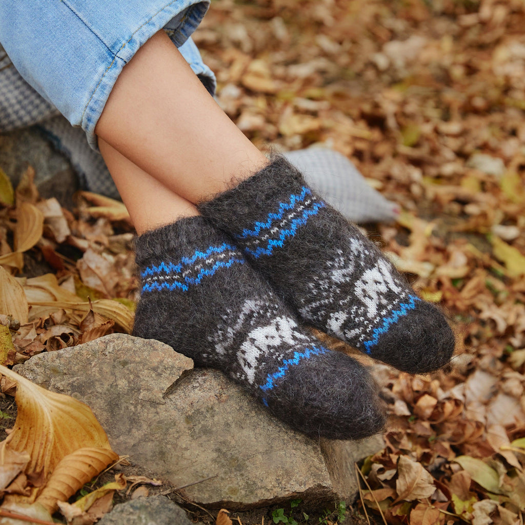 Woman's legs in outdoor settings wearing black and blue goat hair low-cut socks relaxed fit with polar bear design.