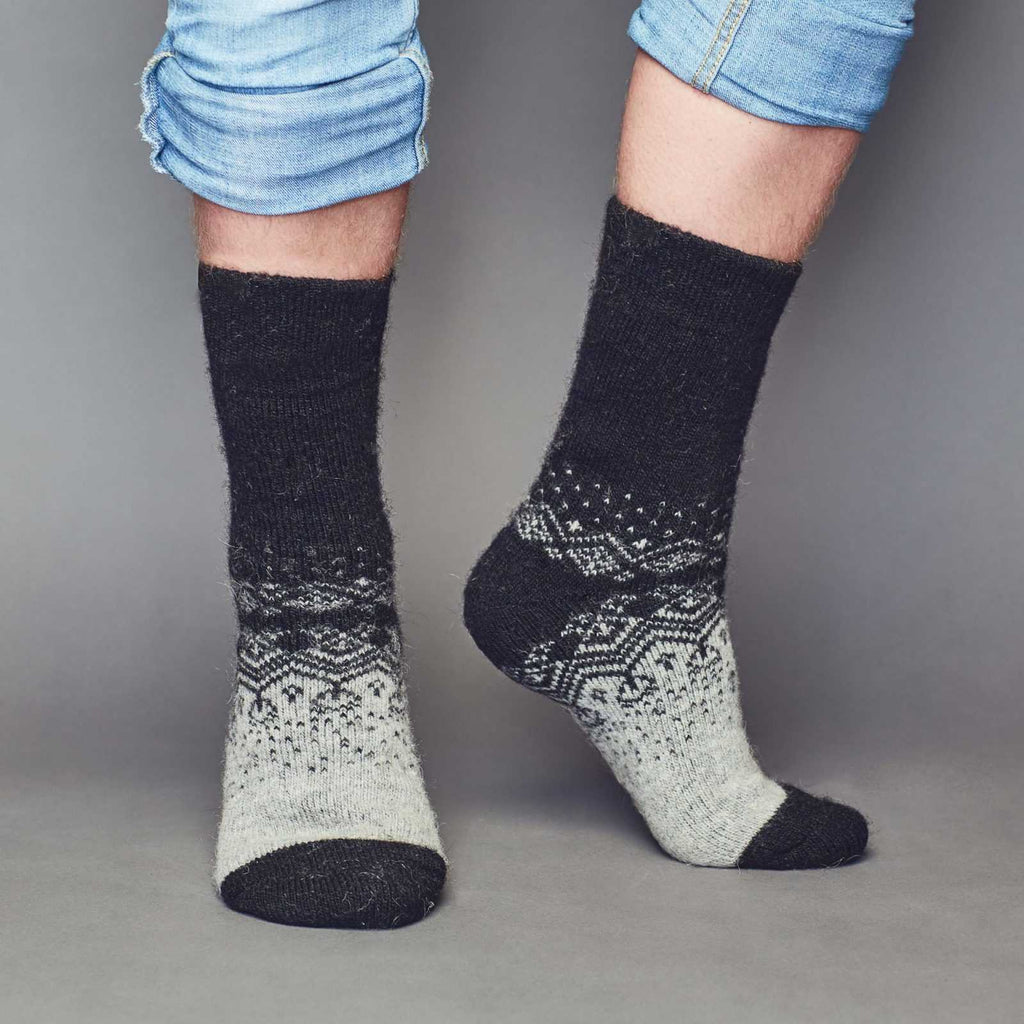 Man’s legs wearing blue jeans and warm merino wool grey-black socks with ornament - front view.