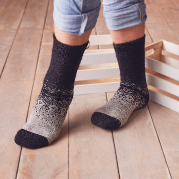 Man’s legs standing wearing warm merino wool grey-black socks with ornament.