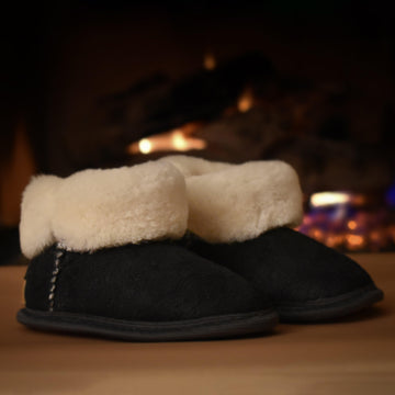 Black sheepskin toddler slippers with white plush fur.