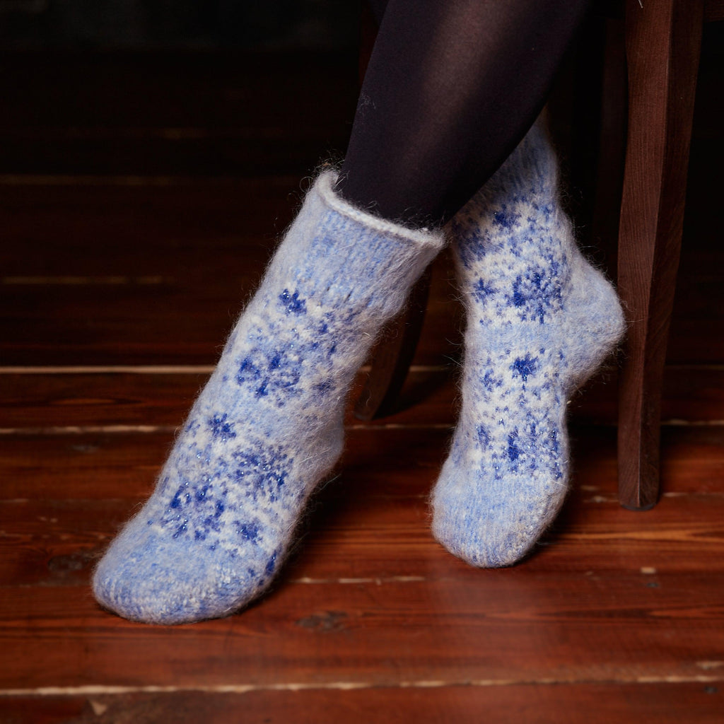 Woman's legs wearing light blue extra thick goat hair crew socks with blue snowflakes.