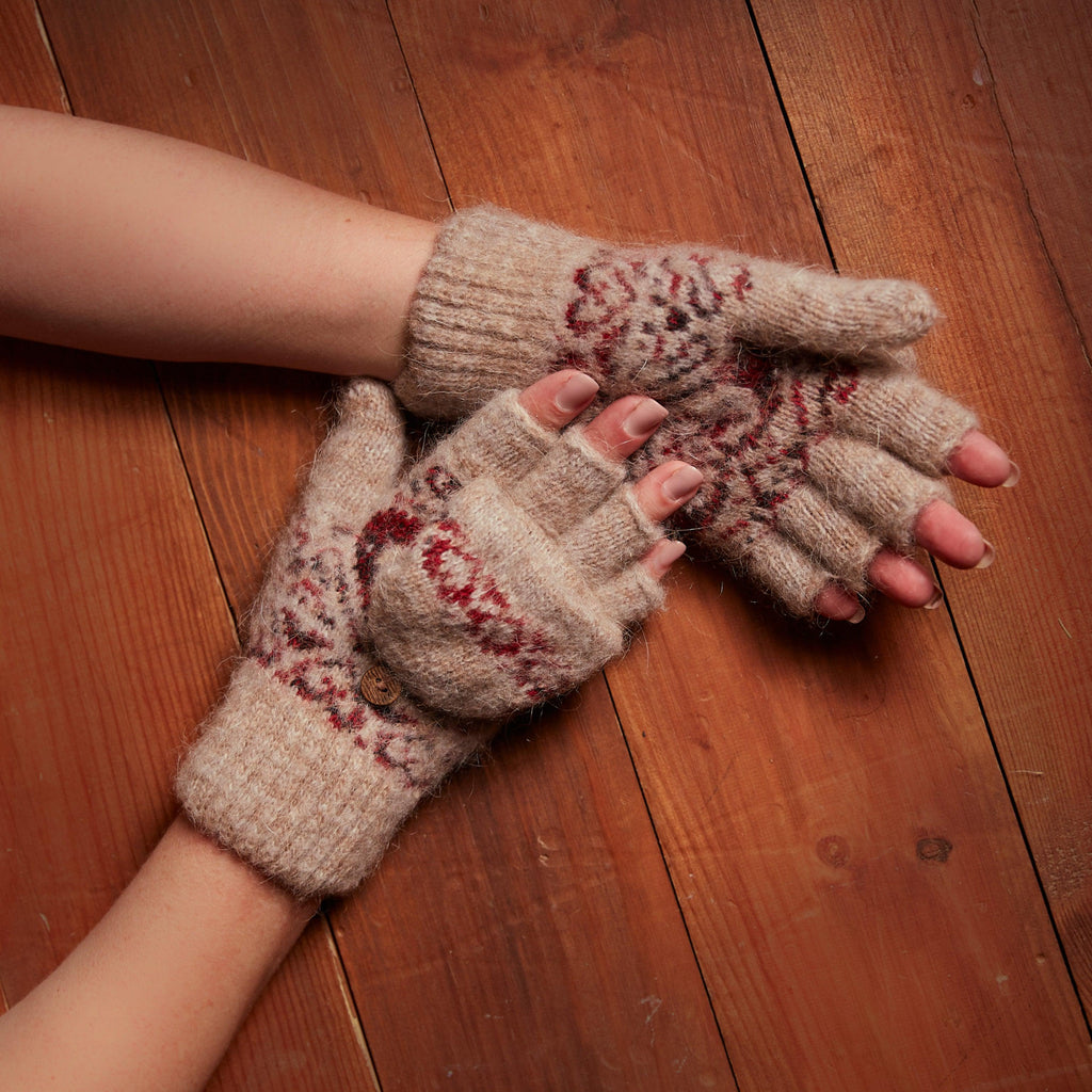 Person's hands wearing light-brown goat hair fingerless glove with a cover with red and black hearts.