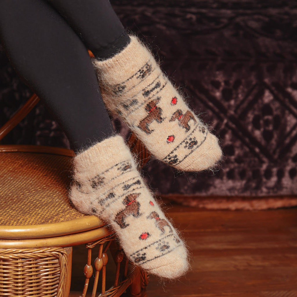 Woman's legs wearing black leggings and camel-colored goat wool socks with puppies and paw-prints design.