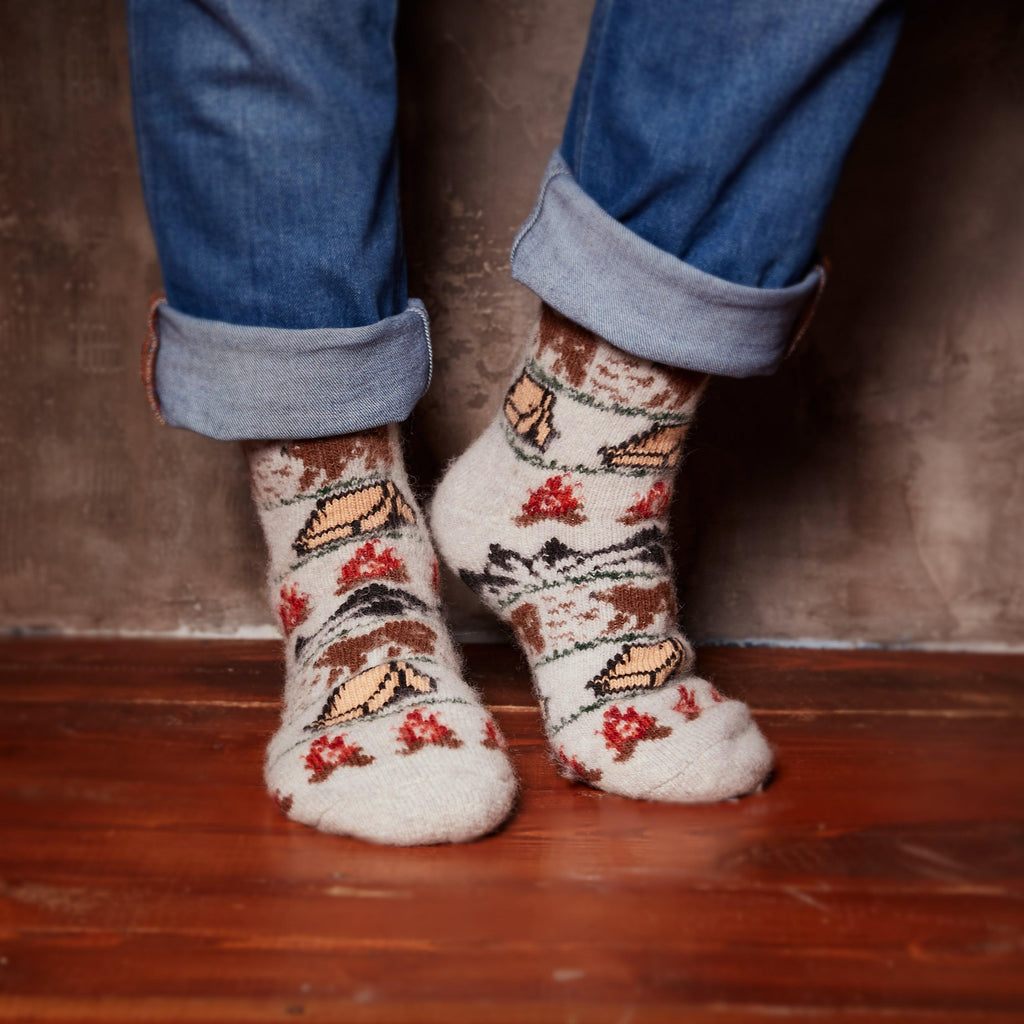 Man’s legs in jeans wearing merino wool crew grey socks with camping design.