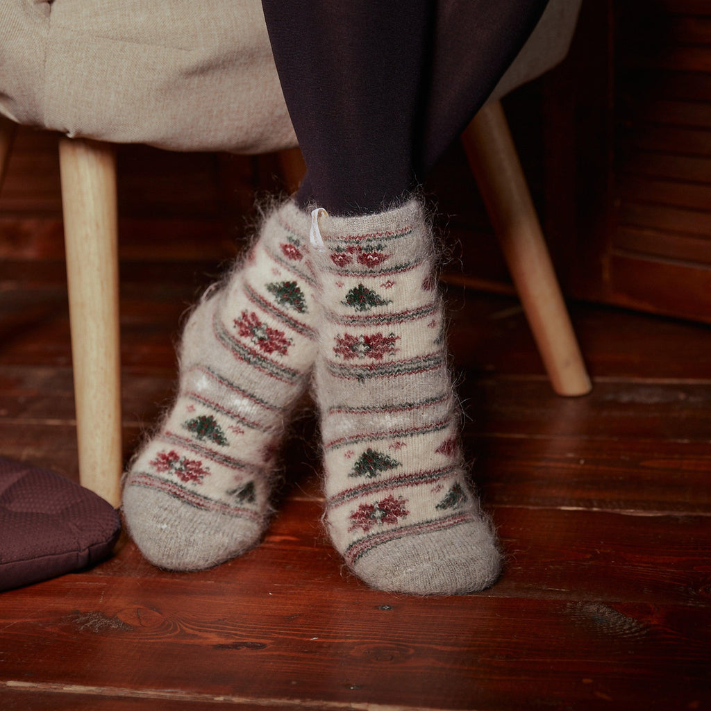 Woman's legs in home interior wearing black leggings and white, gray goat hair socks crew length with Christmas design.