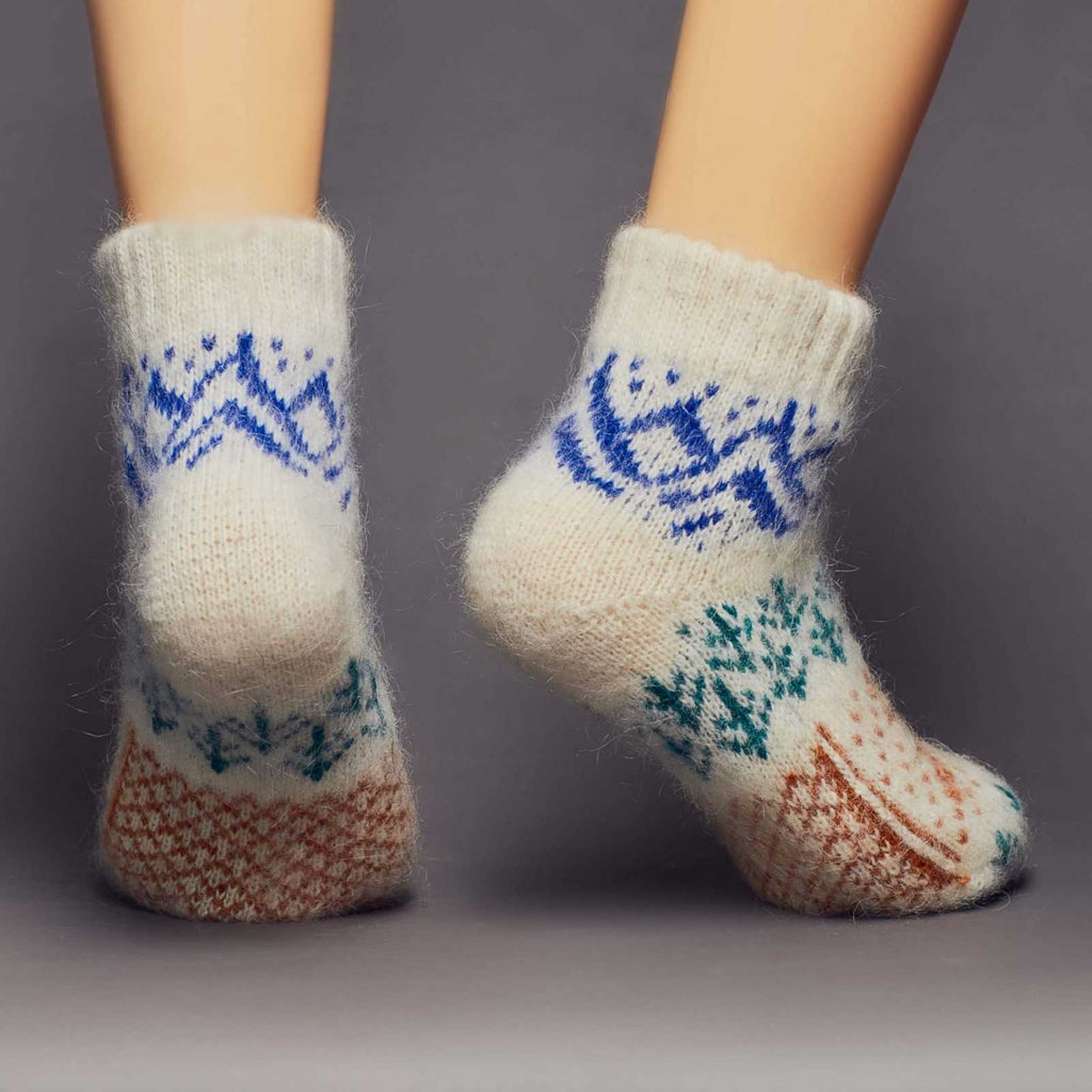 Low-cut warm goat hair off-white socks with a brown deer, green forest, blue mountains design – back view.