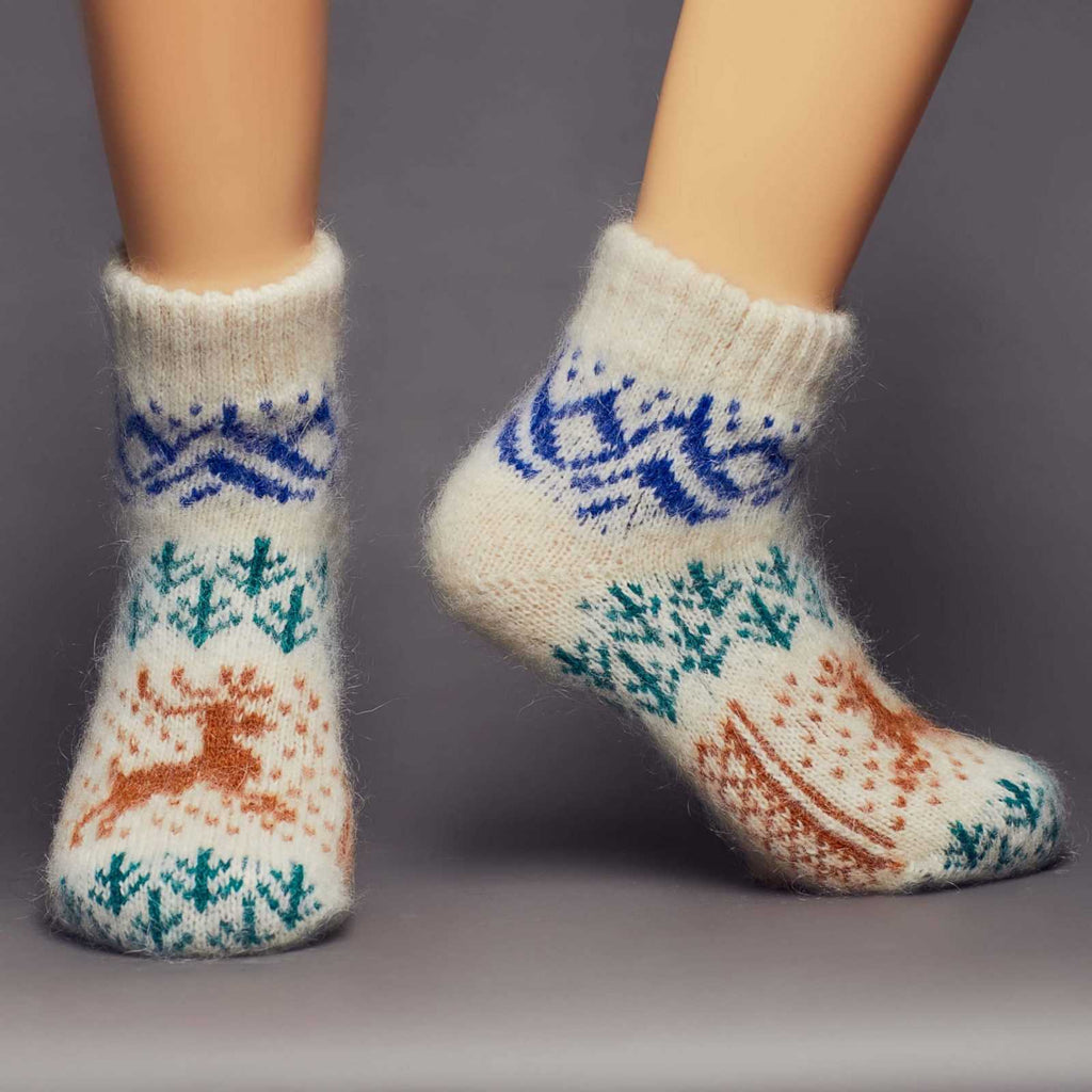 Low-cut warm goat hair off-white socks with a brown deer, green forest, blue mountains design - front view.