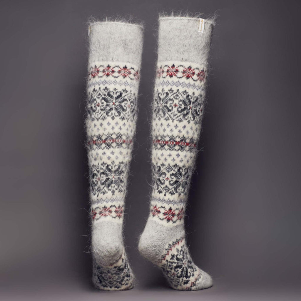 Pair of warm light-grey and white goat wool over-the-knee socks with black and maroon ornaments - back view.