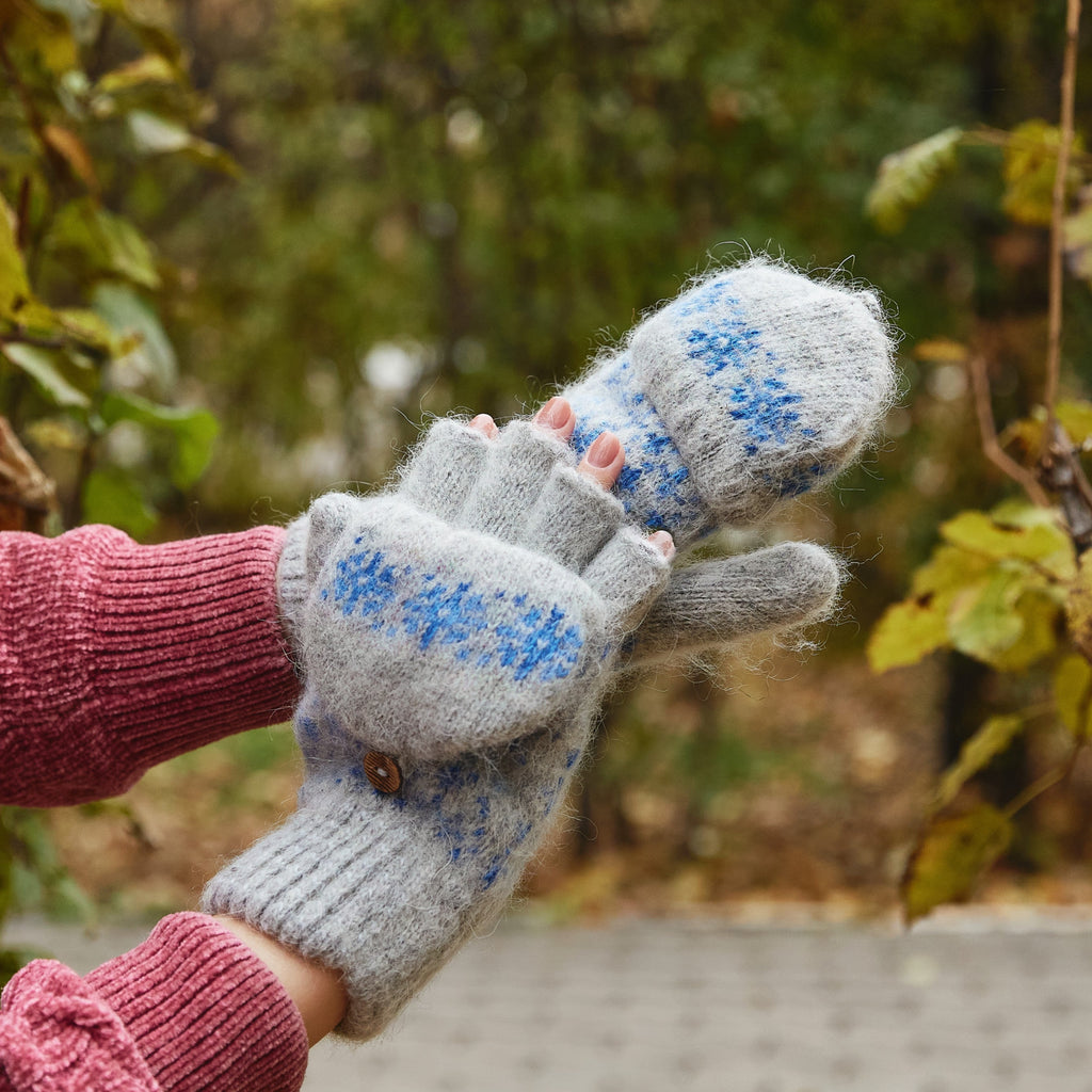Person wearing gray fingerless goat hair gloves with a cover with blue snowflakes.