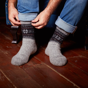 Man's legs posing wearing jeans and grey sheep wool socks relaxed fit with a black, grey, and burgundy geometric ornament.