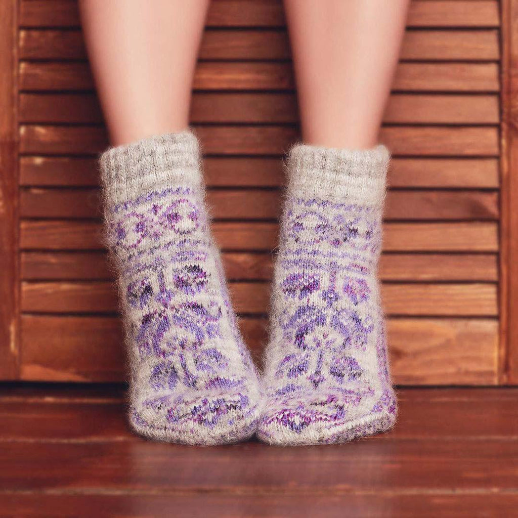 Woman’s legs in home interior wearing low-cut grey goat hair socks with a purple tulip design.
