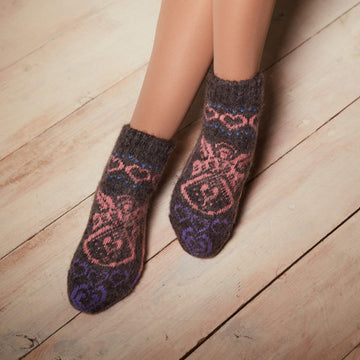Woman's legs wearing dark low-cut goat wool socks with pink angels and purple hearts design.