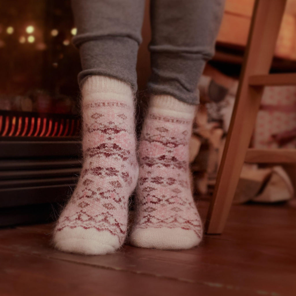 Woman's legs posing wearing grey pants and white crew goat wool socks with pink design.