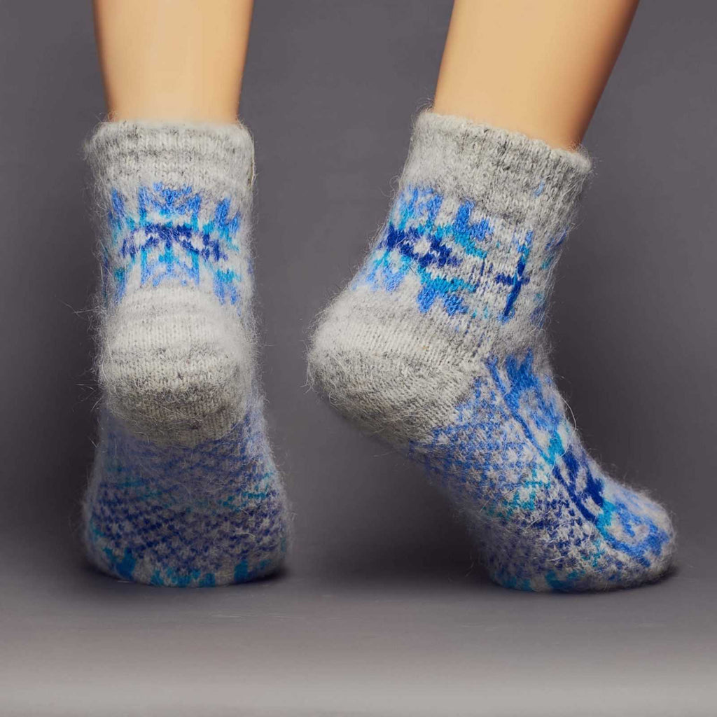 Low-cut grey goat wool home socks with a large blue snowflake design - back view.