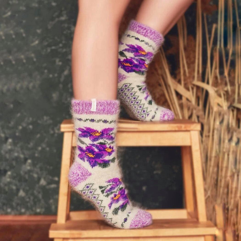 Woman’s legs standing on a chair wearing purple and white wool socks crew length with flower design.