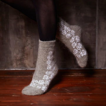 Woman’s legs posing wearing black leggings and grey goat hair socks crew length with white rose pattern.