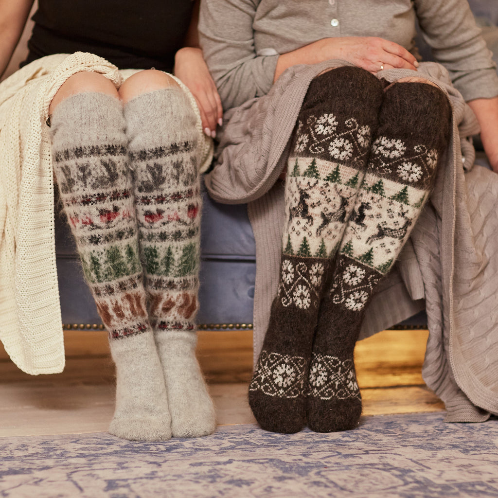 Two women sitting on a couch wearing fuzzy goat hair over-the-knee white-grey and black socks with animal designs.